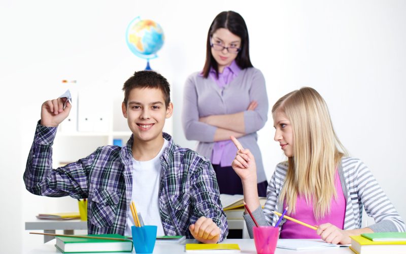Portrait of happy guy playing with paper plane at lesson